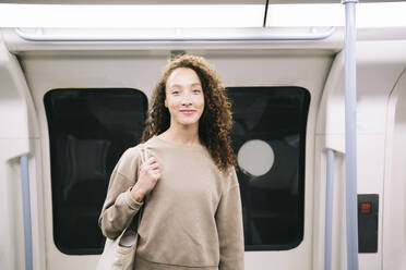 Smiling young woman traveling in subway train - AMWF00886