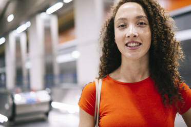 Happy woman with curly hair at subway station - AMWF00896