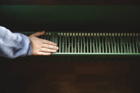 Hand of boy touching radiator at home - EYAF02229