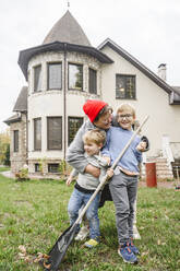 Glückliche Mutter umarmt Jungen, die vor einem Haus im Hinterhof stehen - EYAF02241