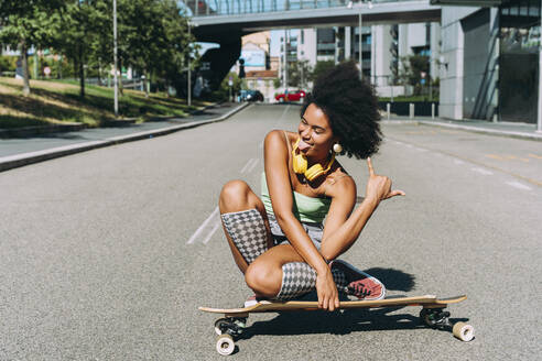 Frau sitzt auf Skateboard und genießt auf der Straße - OIPF02438