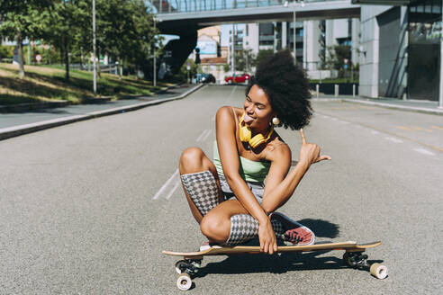 Woman sitting on skateboard and enjoying on street - OIPF02438