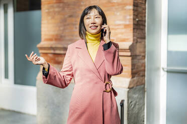 Happy young woman talking over mobile phone on sunny day - DLTSF03163