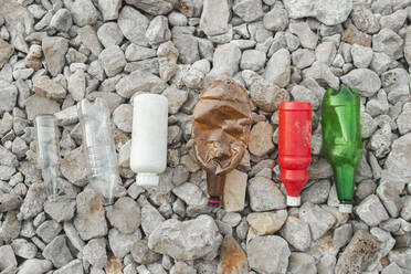 Empty plastic bottles on stones at beach - PCLF00188