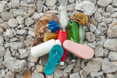 Plastic garbage pile on stones at beach - PCLF00189