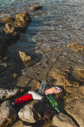 Leere Plastikflaschen und Hausschuhe, die am Strand auf dem Wasser treiben - PCLF00191