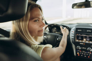 Thoughtful woman holding steering wheel sitting in car - SIF00510