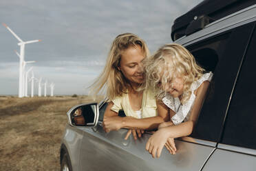 Smiling woman and daughter leaning through car window - SIF00514