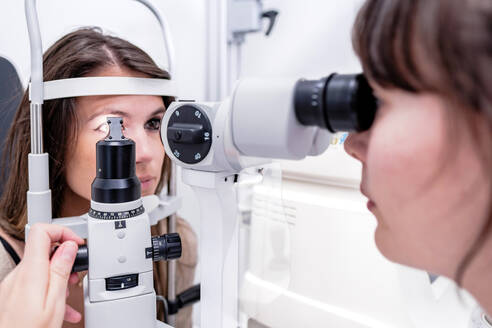 Ärztin mit modernem Tonometer zur Bestimmung des Augeninnendrucks einer Frau bei der Arbeit in einer Augenklinik - ADSF39644
