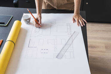 Architect working on blueprint leaning on table - PNAF04606