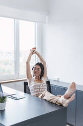 Customer service representative stretching arms in office - PNAF04613