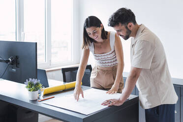 Junger Architekt mit Kollege bei der Besprechung eines Entwurfs im Büro - PNAF04615