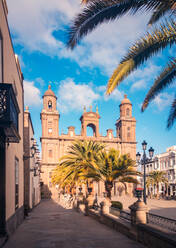 Kathedrale Santa Ana an einer sonnenbeschienenen Straße mit tropischen Palmen vor bewölktem blauem Himmel in Las Palmas, Gran Canaria, Spanien - ADSF39683