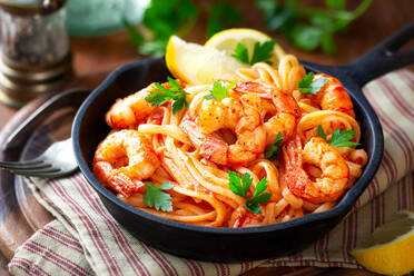 From above spaghetti with shrimps or prawns in tomato sauce garnished with parsley and wedges of lemon - ADSF39686