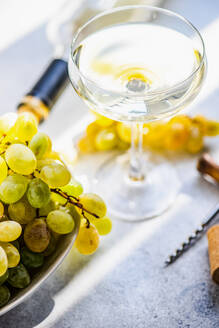 Georgischer Mtsvane-Wein im Glas und frische rohe Trauben auf einem rustikalen Tisch - ADSF39789
