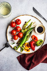 Healthy dinner with bbq bamia, paprika peppers and cherry tomatoes with soy and balzamico sauces served with glass of cold dry wine - ADSF39791