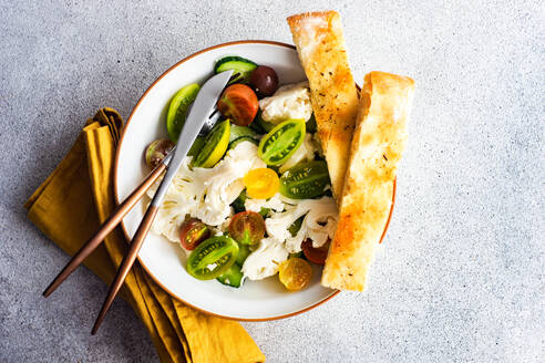 Gesunder Gemüsesalat in der Schüssel und frisch gebackenes Focaccia-Brot auf dem Betontisch serviert - ADSF39795