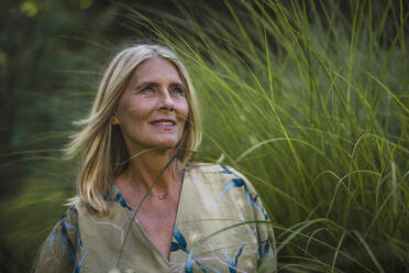 Contemplative mature woman with blond hair in garden - RIBF01086