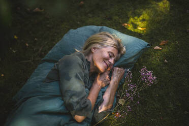 Smiling mature woman sleeping in garden - RIBF01154