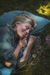 Happy mature woman sleeping in garden - RIBF01155