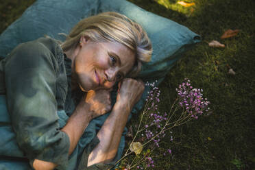 Mature woman lying by flowers in garden - RIBF01156