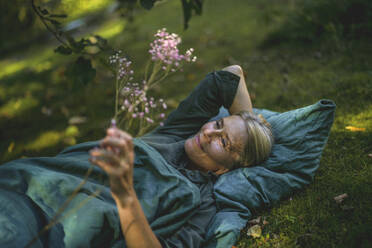 Contemplative mature woman lying in garden - RIBF01158