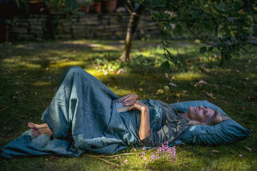 Smiling woman lying down in garden - RIBF01163