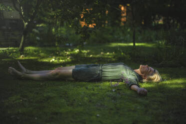 Woman with arms outstretched lying on grass - RIBF01173