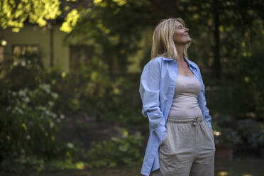 Frau mit blondem Haar im Garten stehend - RIBF01194