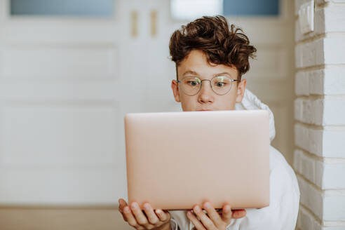 Schockierter Junge mit Laptop zu Hause - MDOF00076