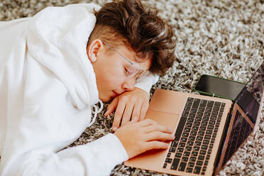 Boy sleeping in front of laptop on carpet - MDOF00099