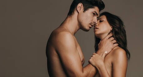 Junger Mann und Frau küssen sich auf braunem Hintergrund. Intimes junges Paar beim Küssen. - JLPSF11364