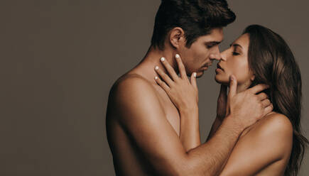 Liebespaar küsst sich mit Leidenschaft und Liebe. Romantisches Paar küsst sich vor braunem Hintergrund. - JLPSF11365
