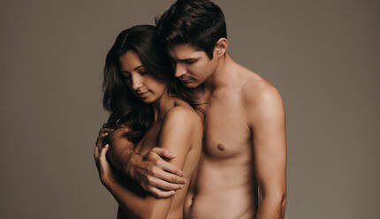 Verliebtes Paar, das zusammen steht. Nackter Mann und Frau umarmen sich auf braunem Hintergrund. - JLPSF11371