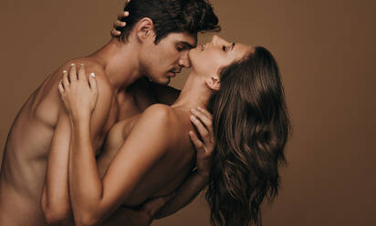 Sinnliches junges Paar vor braunem Hintergrund. Romantischer Mann und Frau teilen einen intimen Moment. - JLPSF11387