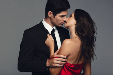 Man seducing woman. Loving young couple kissing. Young man and woman in love kissing against grey background. - JLPSF11423