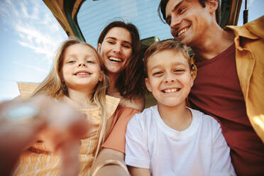 Ein Selfie aus der Handy-Perspektive machen. Glückliche Familie schaut auf die Kamera und macht ein Foto im Urlaub. - JLPSF11460