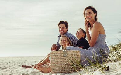 Familie sitzt am Strand und hat Spaß. Familie genießt ein Sommerwochenende am Strand. - JLPSF11468