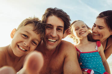 Familie schaut in die Kamera und macht ein Selfie. Point of view shot der Familie, die in die Kamera schaut und ihren Sommerurlaub genießt. - JLPSF11473