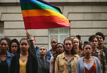 Menschen nehmen an der Pride-Parade teil. Multiethnische Menschen auf der Straße mit einer Frau, die eine schwule Regenbogenfahne schwenkt. - JLPSF11489