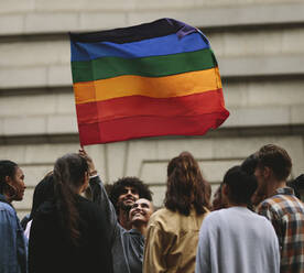 Menschen nehmen an der jährlichen Pride-Parade und den Feierlichkeiten in der Stadt teil. Junge Frau schwenkt schwule Regenbogenfahne mit herumstehenden Menschen. - JLPSF11490