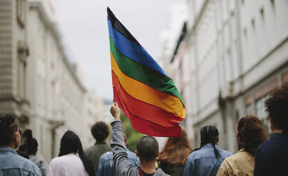 Rückansicht von Menschen in der Pride Parade. Gruppe von Menschen auf der Straße der Stadt mit Homosexuell Regenbogenflagge. - JLPSF11493