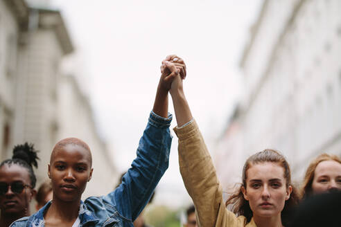 Group of activists with holding hands protesting in the city. Rebellions doing demonstration on the street holding hands. - JLPSF11500