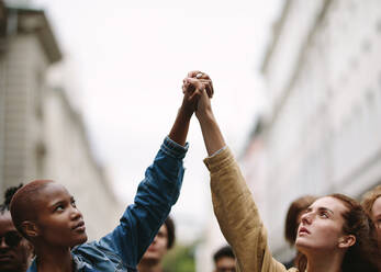 Zwei Aktivistinnen halten sich an den Händen und protestieren. Demonstranten bei einer Demonstration auf der Straße halten sich an den Händen. - JLPSF11501