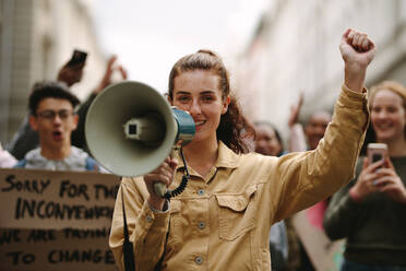 Moderne städtische Frau, die bei einem Streik protestiert und ihre Beschwerden in ein Megaphon schreit. Weibliche Aktivistin, die während eines Streiks mit einem Megaphon protestiert. - JLPSF11514
