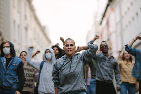 Group of men and women marching on street and giving slogans. Activists having a protest rally in the city. - JLPSF11533