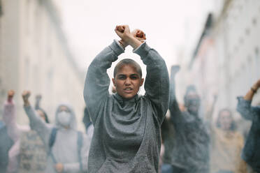 Eine weibliche Aktivistin protestiert bei einem Streik mit über dem Kopf gekreuzten Händen. Eine Frau protestiert und gibt Slogans in der Stadt von sich. - JLPSF11541