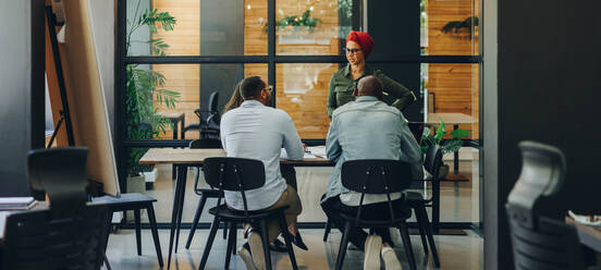 Geschäftsfrau bei einer Diskussion mit ihrem Team während einer Bürobesprechung. Muslimische Geschäftsfrau beim Austausch strategischer Ideen mit ihren Kollegen. Teamleiterin mit Kopftuch an einem integrativen Arbeitsplatz. - JLPSF11638