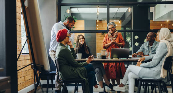 Happy businesspeople smiling cheerfully during a meeting in a creative office. Group of successful business professionals working as a team in a multicultural workplace. - JLPSF11648