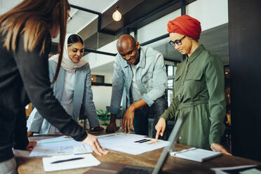 Innovative Innenarchitekten diskutieren während einer Besprechung in einem modernen Büro über Farbpaletten. Eine Gruppe von multikulturellen Geschäftsleuten tauscht kreative Ideen an einem integrativen Arbeitsplatz aus. - JLPSF11702